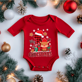 Red baby onesie with Christmas design surrounded by festive decorations on a white background