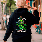 Person wearing a black hoodie with a green character design and text on the back, walking outdoors.