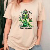 Person wearing a beige t-shirt with a green alien character and text design.