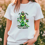 Person wearing a white t-shirt with a green character and text graphic, standing outdoors.