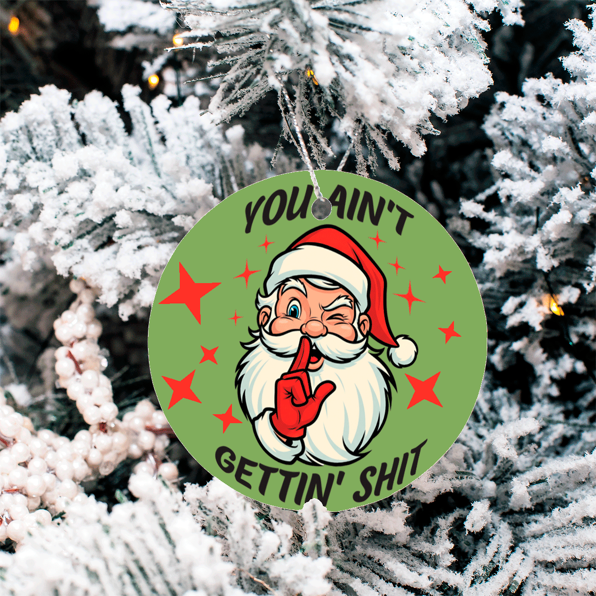Christmas ornament with Santa Claus graphic and text 'YOU AIN'T GETTIN' SHIT' on a snow-covered tree.