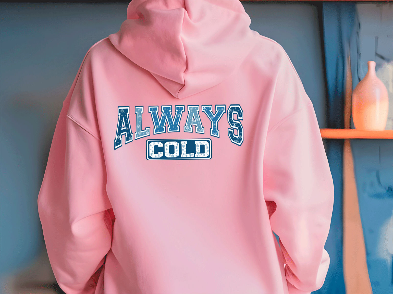 Pink hoodie with 'ALWAYS COLD' text on a blue wall background