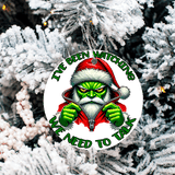 Christmas ornament with Grinch character and text 'I've been watching. We need to talk' on a snowy tree background.