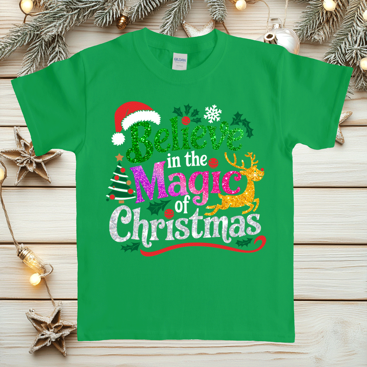 Green t-shirt with Christmas-themed text and graphics on a wooden surface with festive decorations.