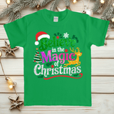 Green t-shirt with Christmas-themed text and graphics on a wooden surface with festive decorations.