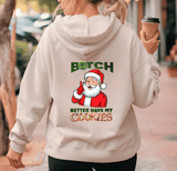Person wearing a hoodie with a graphic of Santa Claus and text, holding a coffee cup.