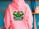 Pink hoodie with a graphic of a green character flexing muscles and the text 'Big Grinch Energy' on the back, against a blue wall.