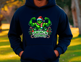 Person wearing a navy blue hoodie with a Christmas-themed graphic of a green character flexing muscles, surrounded by candy canes and the text 'Big Grinch Energy'.