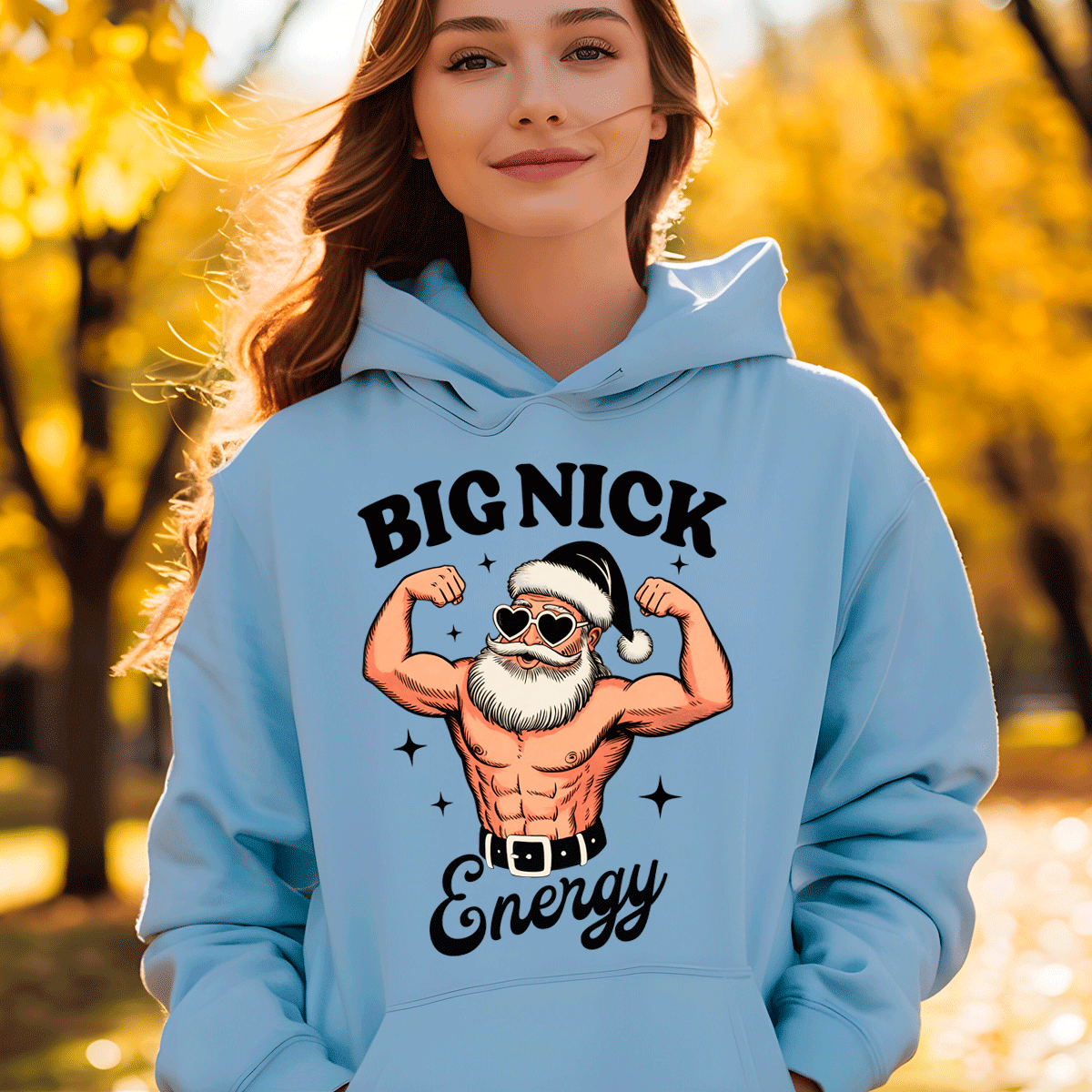 Person wearing a light blue hoodie with a graphic design of a muscular Santa Claus and text 'BIG NICK Energy' in an outdoor setting.