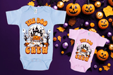 Two Halloween-themed baby onesies on a purple background with pumpkins and leaves.