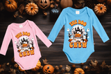 Two Halloween-themed baby onesies, one pink and one blue, with pumpkins in the background.
