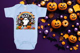 Halloween-themed baby onesie with colorful design on a purple background with pumpkins and decorations.
