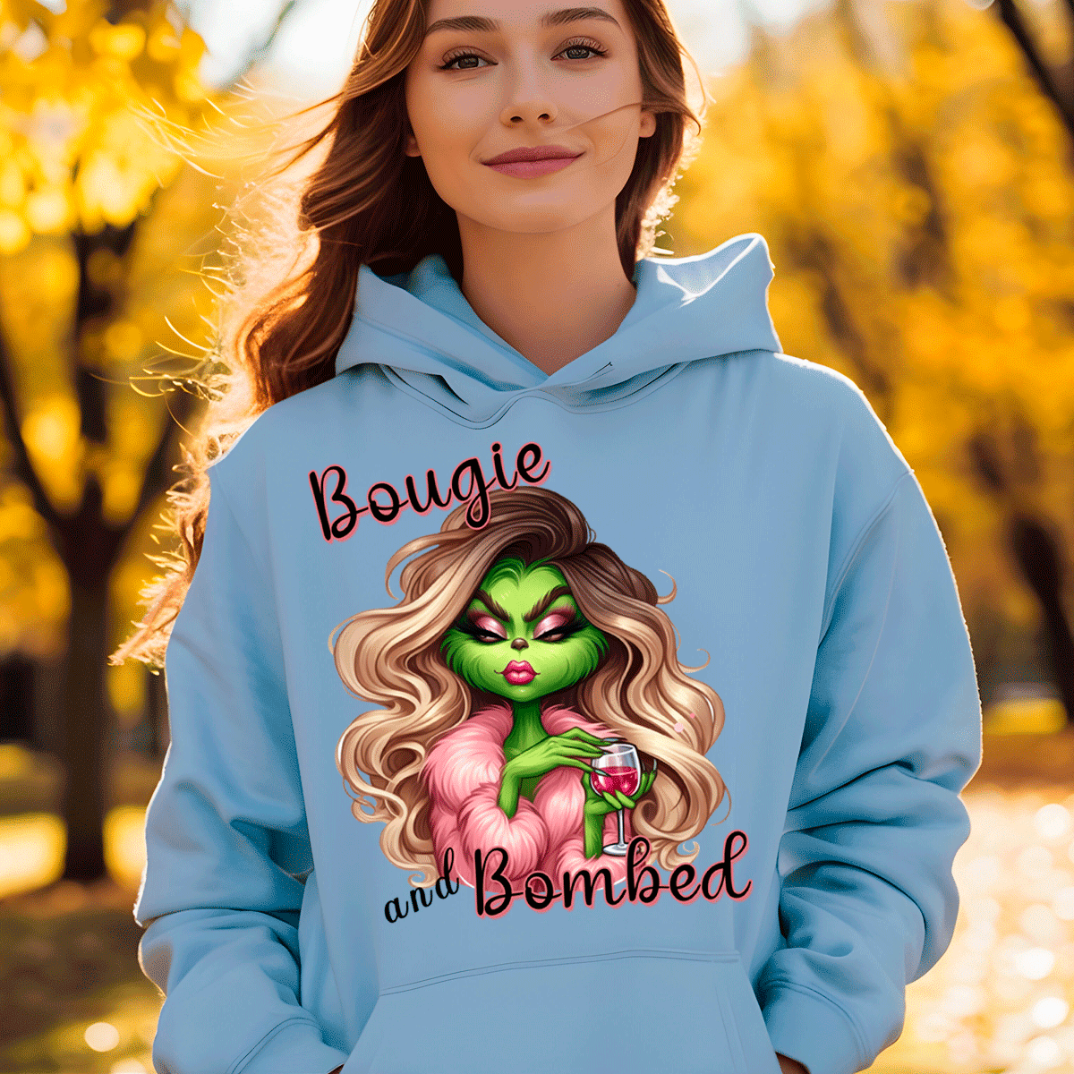 Person wearing a light blue hoodie with a graphic design and text, standing in an outdoor setting with trees.