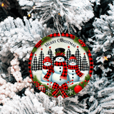 Christmas ornament with snowmen and plaid patterns hanging on a tree.