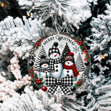 Decorative Christmas ornament with snowmen and 'Merry Christmas' text on a snowy tree background