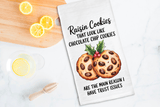 Tea towel with raisin cookies illustration and humorous text on a kitchen counter with lemons.