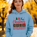 Person wearing a light blue hoodie with Christmas-themed text in an outdoor setting with trees.