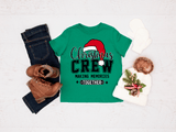 Green t-shirt with 'Christmas Crew' design, paired with jeans, boots, and a hat on a light background