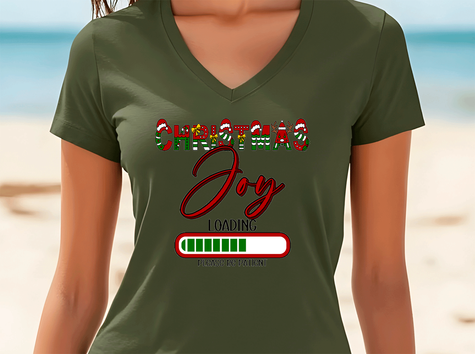 Person wearing a green t-shirt with 'Christmas Joy Loading' text on a beach background