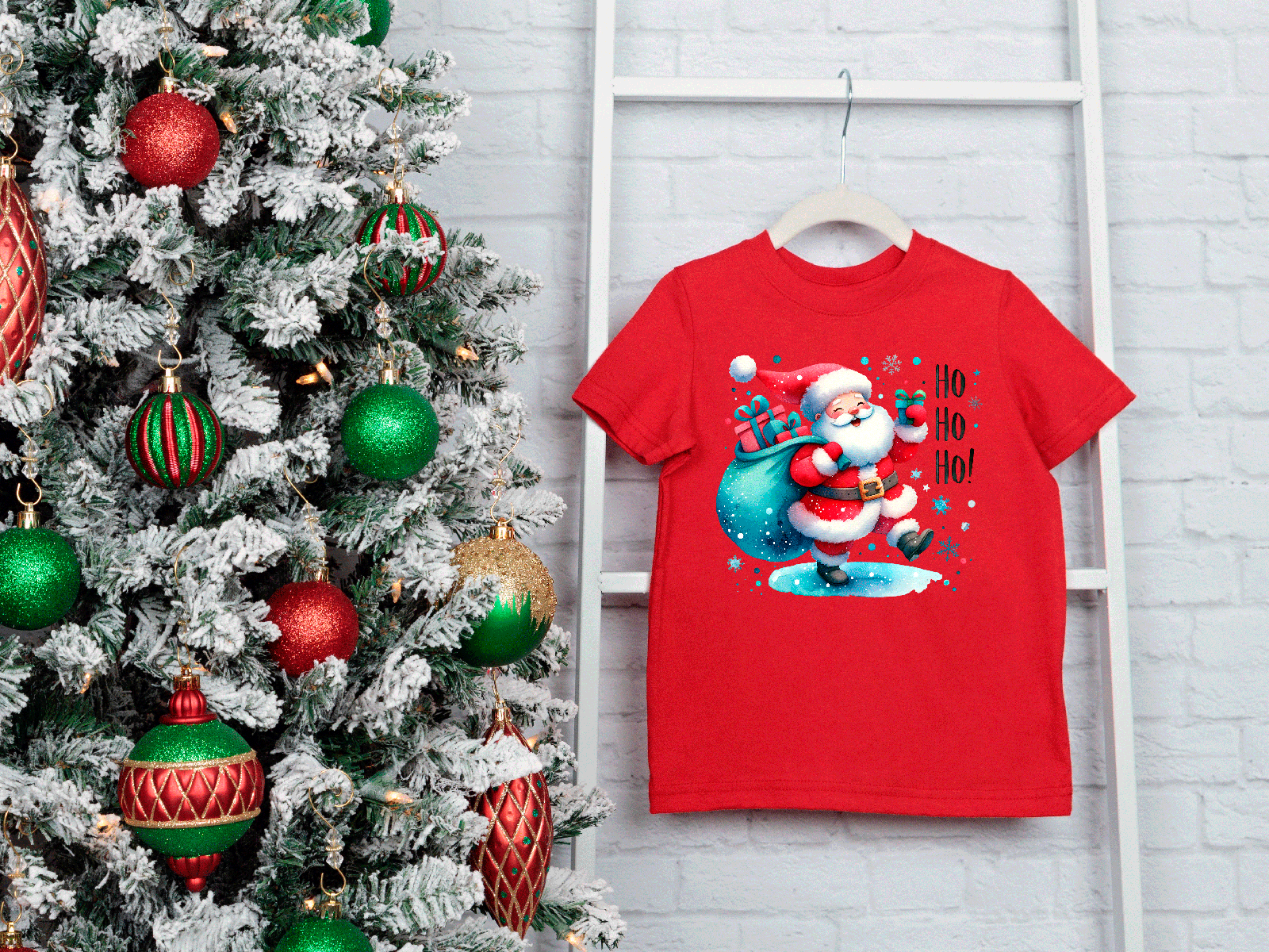 Red t-shirt with Santa Claus design next to a decorated Christmas tree on a white brick wall.