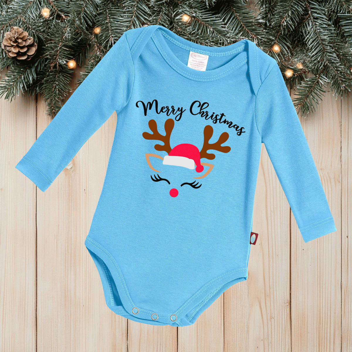 Blue baby onesie with Christmas design on a wooden surface with festive background