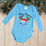 Blue baby onesie with Christmas design on a wooden surface with festive background