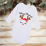 White baby onesie with Christmas design on a wooden surface with pine branches and pinecones.
