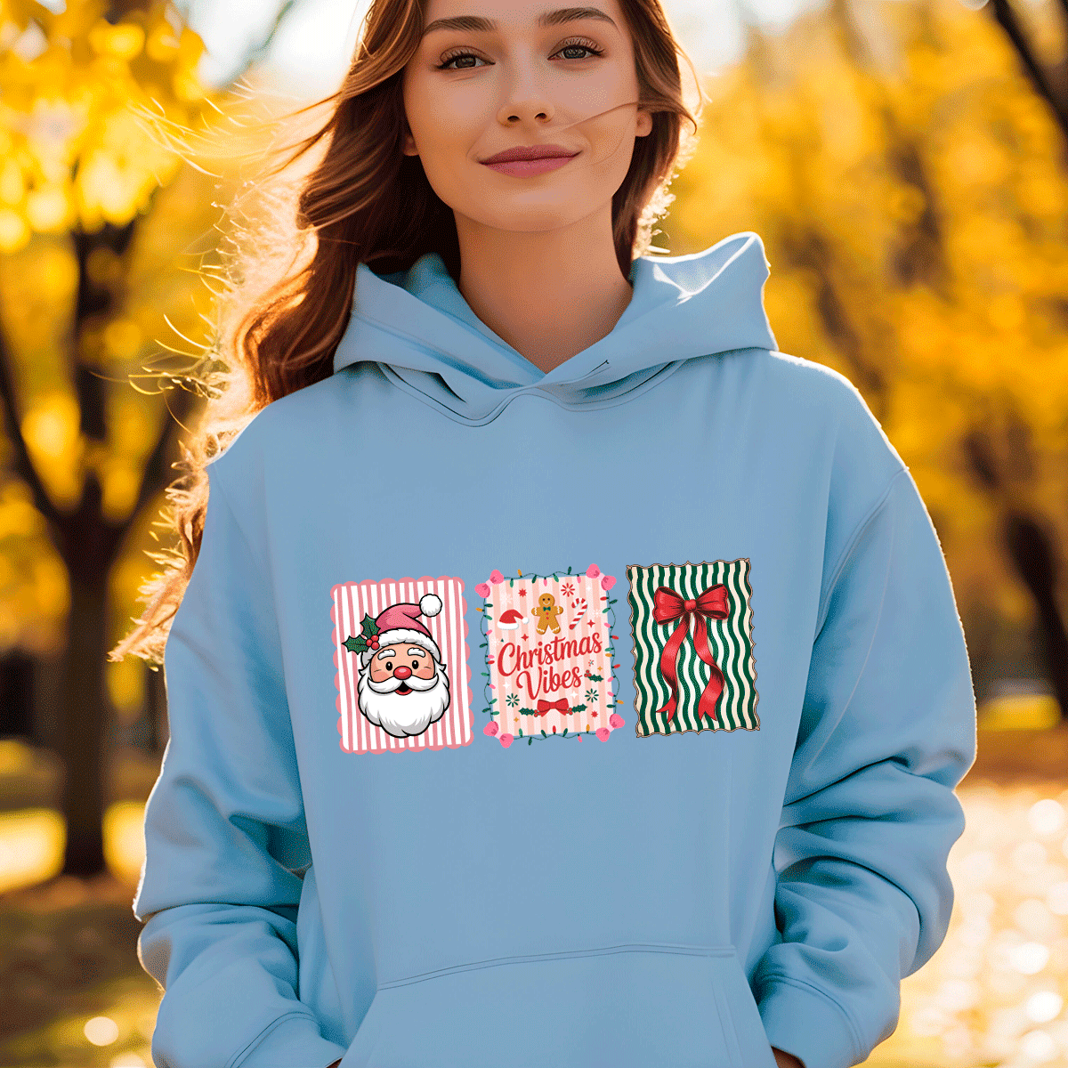 Person wearing a light blue hoodie with Christmas-themed designs outdoors in autumn.