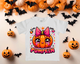 White t-shirt with a colorful pumpkin design surrounded by Halloween decorations on a beige background