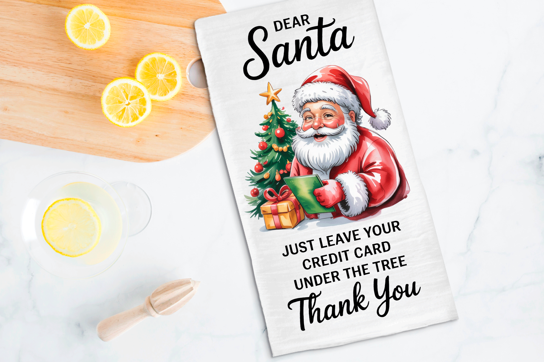 Tea towel with Santa Claus design and humorous text on a kitchen counter with lemons.