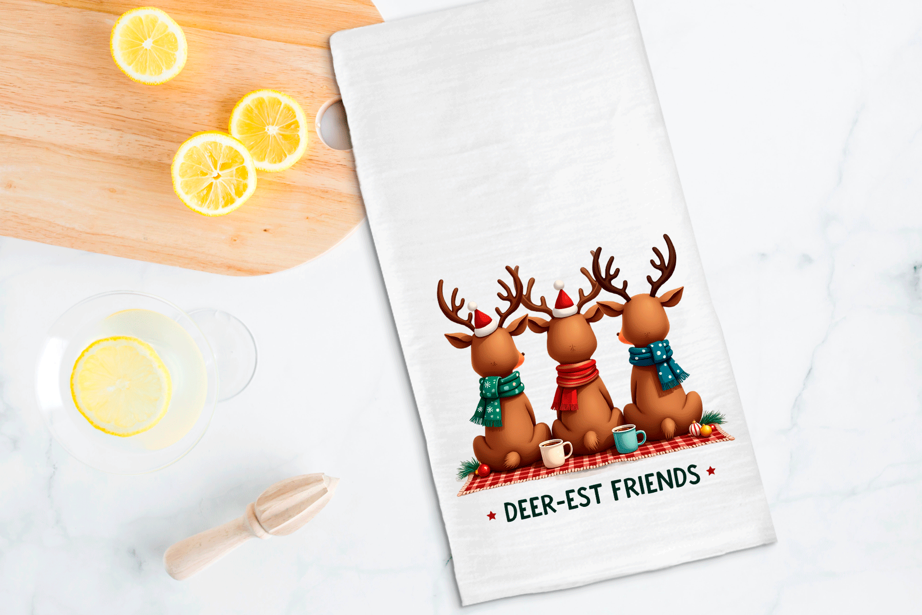 Tea towel with reindeer design and 'Deer-est Friends' text on a kitchen counter with lemons.