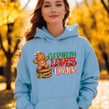 Person wearing a light blue hoodie with a gingerbread design and text in an autumn setting