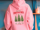 Pink hoodie with Christmas tree design and text on a blue background
