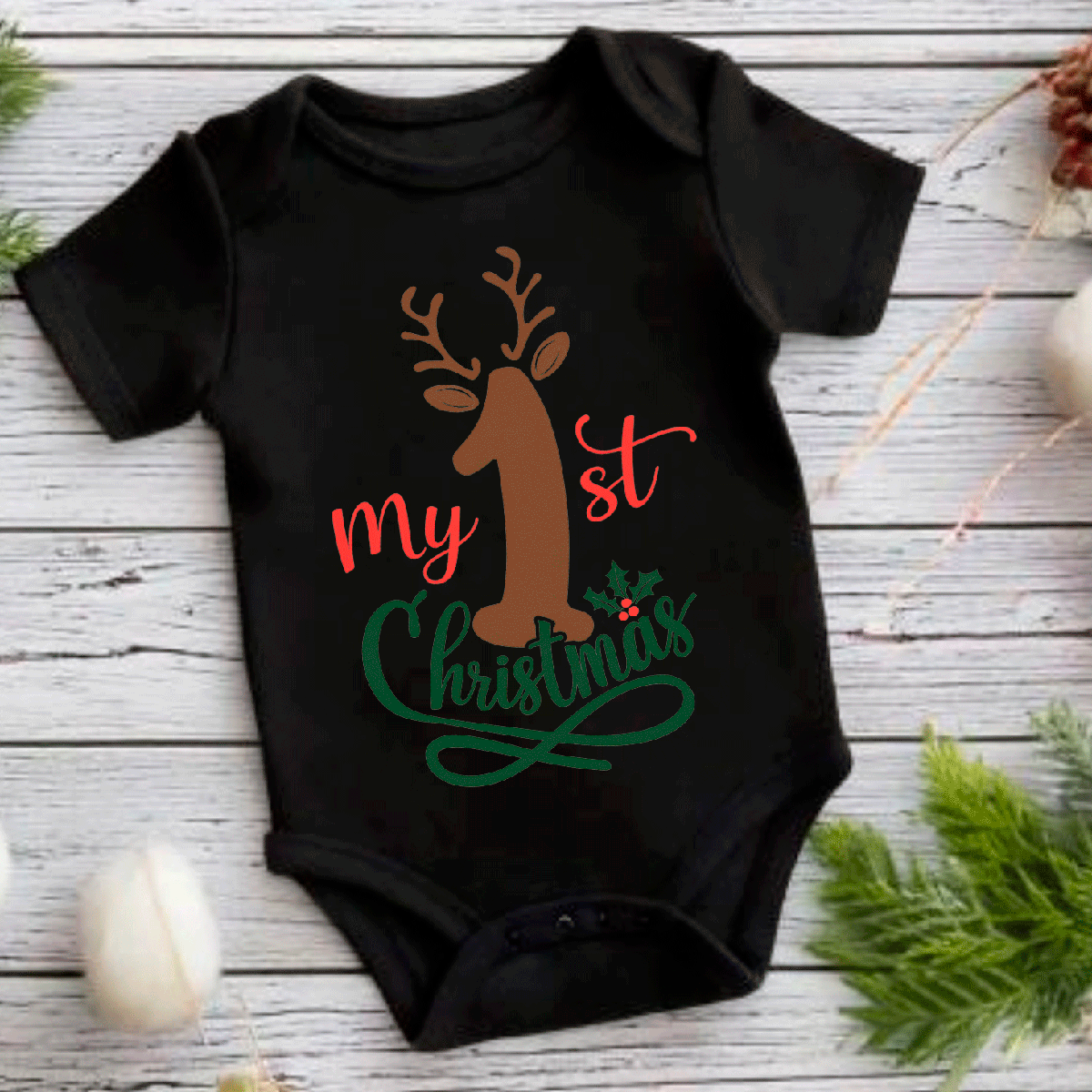 Black baby onesie with reindeer design and 'My 1st Christmas' text on a wooden surface.