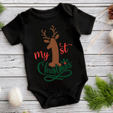 Black baby onesie with reindeer design and 'My 1st Christmas' text on a wooden surface.