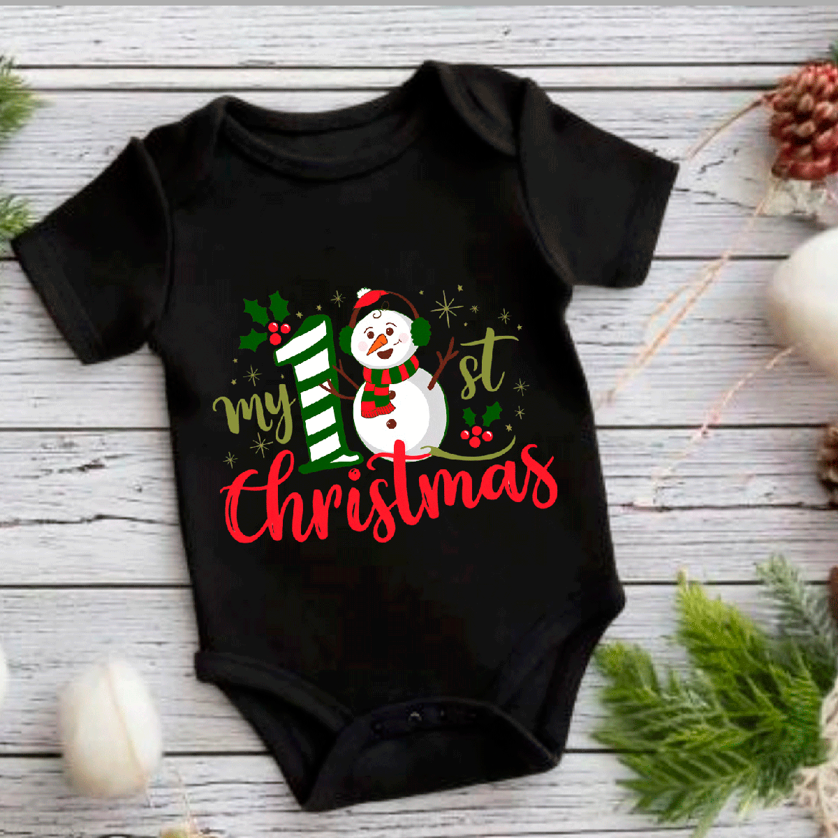 Black baby onesie with a Christmas design featuring a snowman and text on a wooden surface.