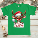 Green t-shirt with a reindeer holding a 'Merry Christmas' sign on a wooden surface with Christmas decorations.