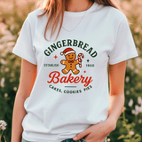 Person wearing a white t-shirt with a gingerbread-themed bakery design.