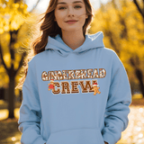 Person wearing a light blue hoodie with 'Gingerbread Crew' text in an autumn setting