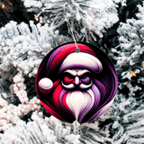 Ornament with a stylized face design hanging on a snow-covered tree.