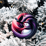 Colorful ornament with a snowman and bird design on a snowy tree background