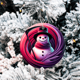 Decorative Christmas ornament with a snowman design on a purple and pink swirl background, hanging on a tree.