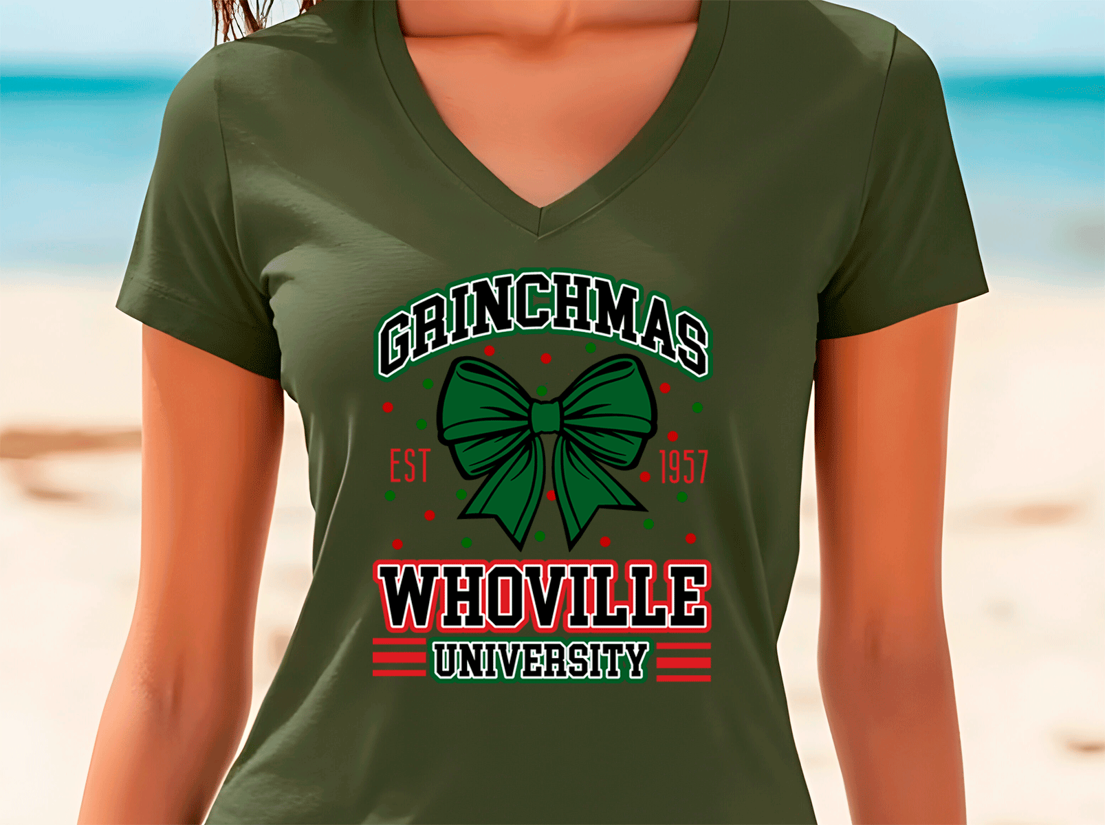 Person wearing a green t-shirt with 'Grinchmas Whoville University' design on a beach.