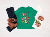 Green t-shirt with Christmas design, jeans, boots, and a hat on a light background