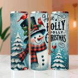 Three Christmas-themed tumblers with snowmen, cardinal birds, and festive text on a blurred indoor background.
