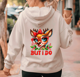 Person wearing a hoodie with a reindeer design and 'BUT I DO' text, holding a coffee cup.