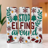 Three white tumblers with Christmas-themed designs and text on a blurred background.
