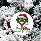 Christmas ornament with Grinch face and text 'is this Jolly enough for you' on a snowy tree background