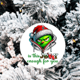 Christmas ornament with Grinch face and text 'is this Jolly enough for you' on a snowy tree background