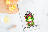 Tea towel with a Grinch design and text on a kitchen counter with lemons.